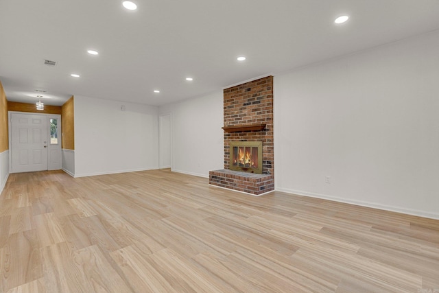 unfurnished living room with light wood finished floors, a brick fireplace, visible vents, and recessed lighting