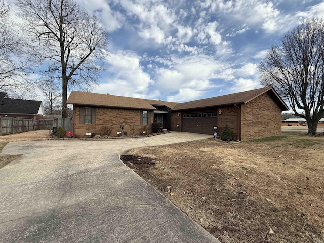 ranch-style home with a garage, concrete driveway, brick siding, and fence