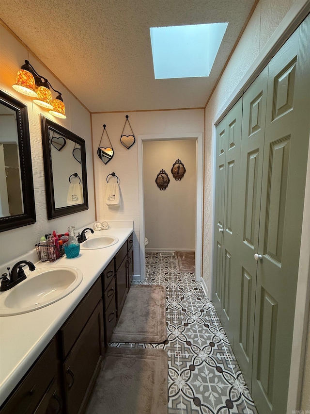 bathroom with a skylight, a sink, a textured ceiling, and double vanity