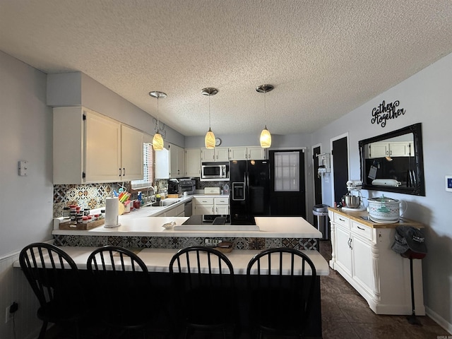 kitchen featuring a peninsula, black appliances, white cabinets, and hanging light fixtures