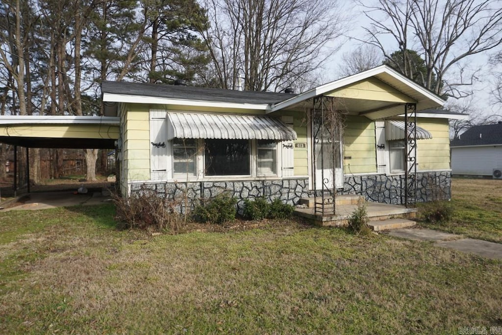 bungalow-style house with stone siding, a carport, and a front yard