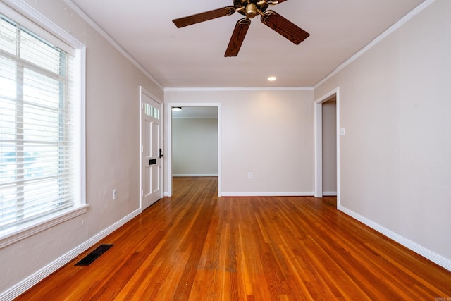 unfurnished room with visible vents, baseboards, ceiling fan, wood finished floors, and crown molding