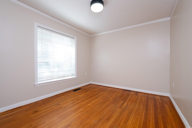 spare room with crown molding, light wood-style flooring, visible vents, and baseboards