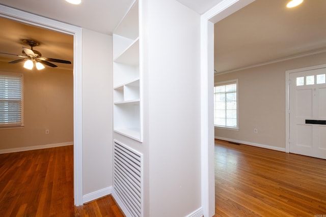 hall featuring crown molding, baseboards, and wood finished floors