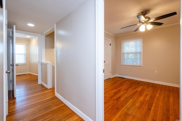 hallway featuring crown molding, baseboards, and wood finished floors