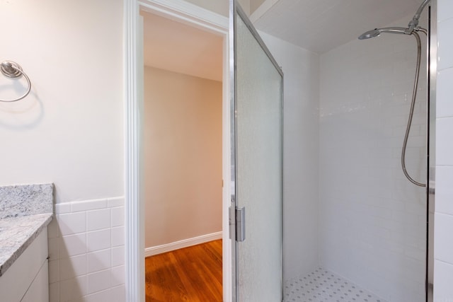 full bath featuring wood finished floors, a shower stall, and vanity