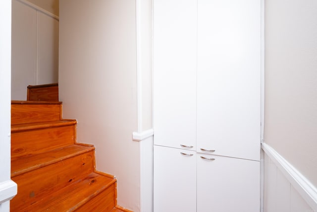 staircase with a wainscoted wall and a decorative wall