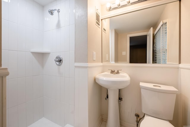 full bathroom featuring toilet, a sink, visible vents, and tiled shower