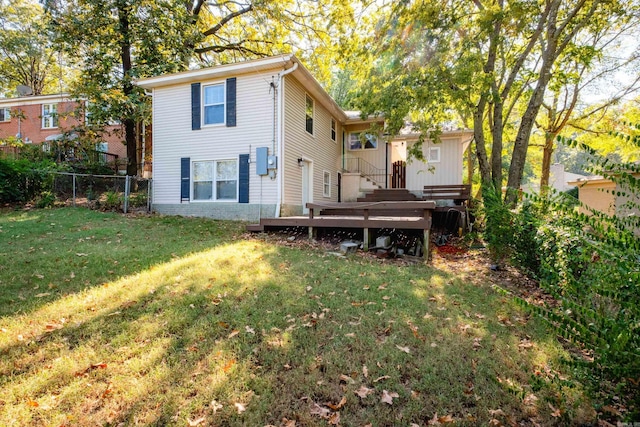 rear view of house with fence, a deck, and a yard