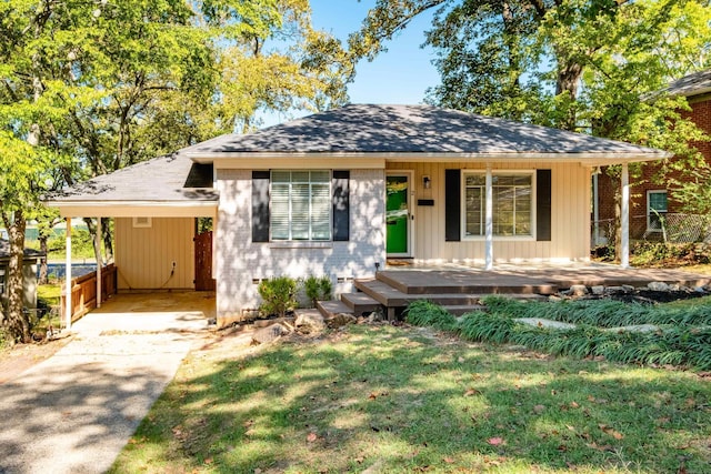 bungalow-style home with driveway, an attached carport, a front lawn, and a porch