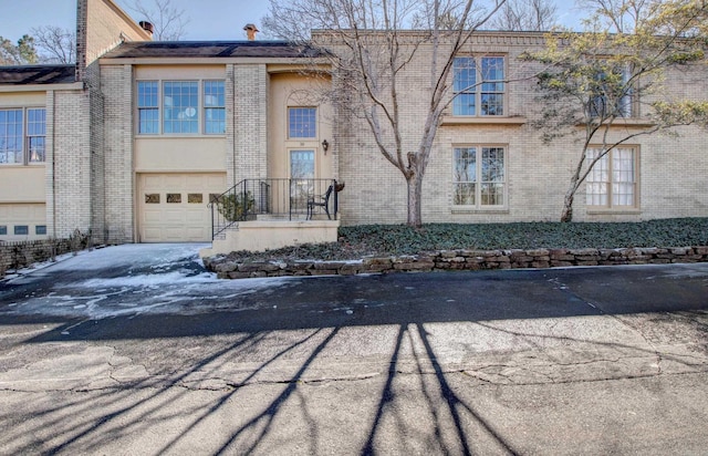 view of front of home featuring a garage, brick siding, and aphalt driveway