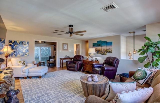 living room with ceiling fan, visible vents, and wood finished floors