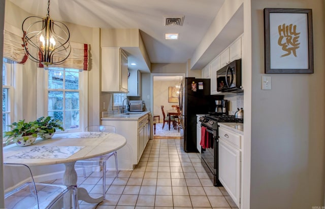 kitchen with light countertops, visible vents, an inviting chandelier, a sink, and black appliances