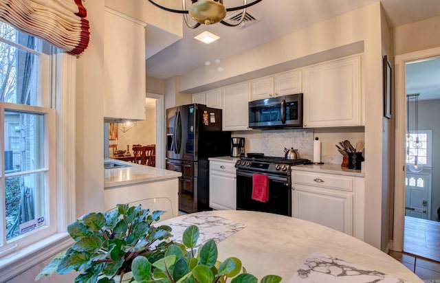 kitchen featuring white cabinets, range with gas stovetop, decorative backsplash, black fridge with ice dispenser, and stainless steel microwave