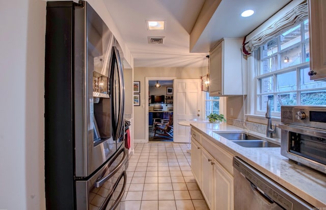 kitchen featuring light tile patterned floors, visible vents, appliances with stainless steel finishes, white cabinets, and a sink