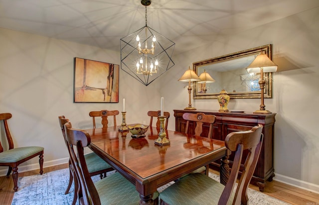 dining space featuring baseboards, a chandelier, and wood finished floors