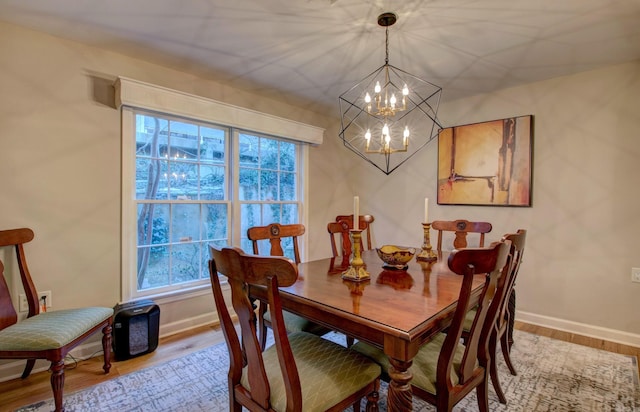 dining space featuring a chandelier, baseboards, and wood finished floors