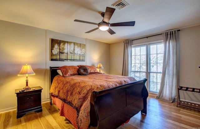 bedroom with baseboards, visible vents, ceiling fan, and wood finished floors