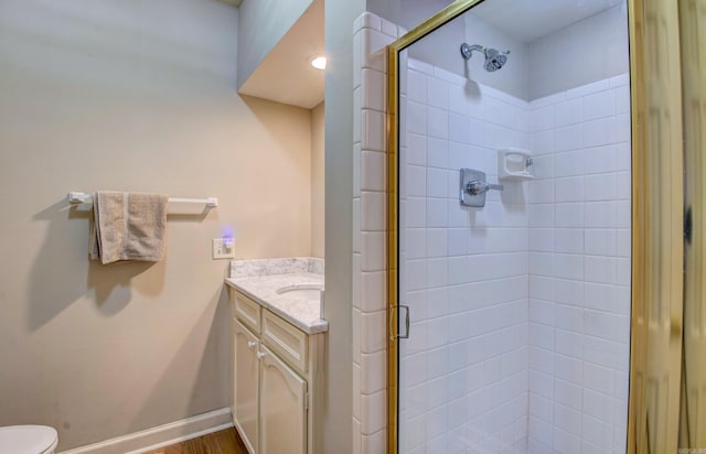 full bathroom with toilet, a stall shower, baseboards, and vanity