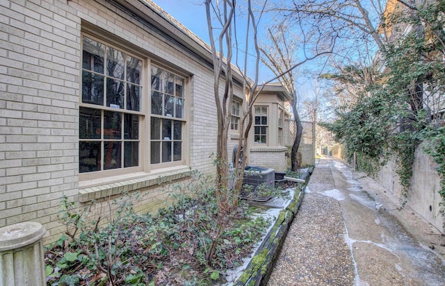 view of side of home featuring brick siding and fence