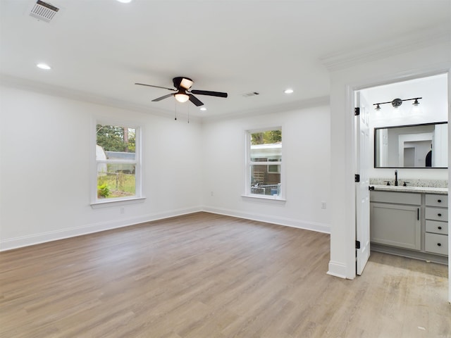 interior space featuring a healthy amount of sunlight, light wood-type flooring, visible vents, and crown molding