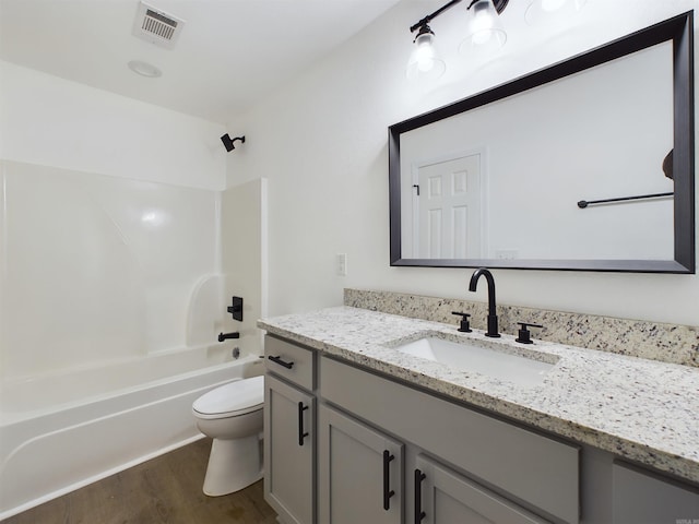 full bathroom with visible vents, shower / bathing tub combination, toilet, vanity, and wood finished floors