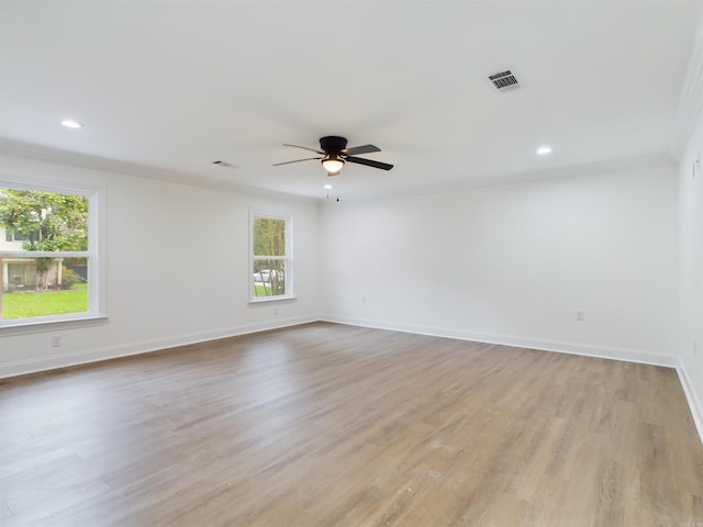 unfurnished room with ceiling fan, light wood-style flooring, visible vents, baseboards, and crown molding