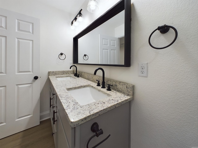 bathroom with double vanity, a sink, and wood finished floors