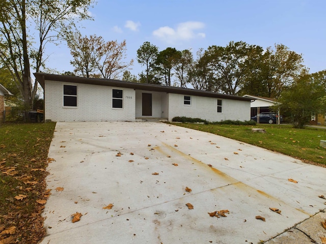 ranch-style home with driveway, brick siding, and a front yard