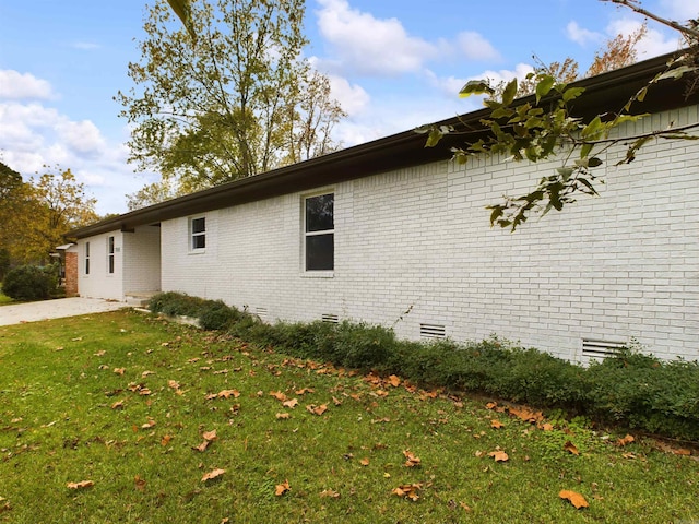 view of property exterior with crawl space, brick siding, and a lawn