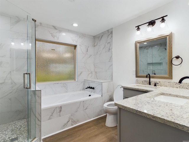 bathroom featuring a garden tub, toilet, wood finished floors, vanity, and a stall shower