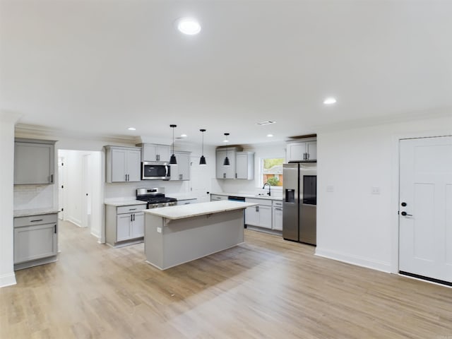 kitchen with stainless steel appliances, gray cabinets, decorative backsplash, a sink, and a kitchen island