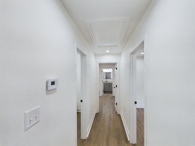 corridor featuring wood finished floors, attic access, and baseboards