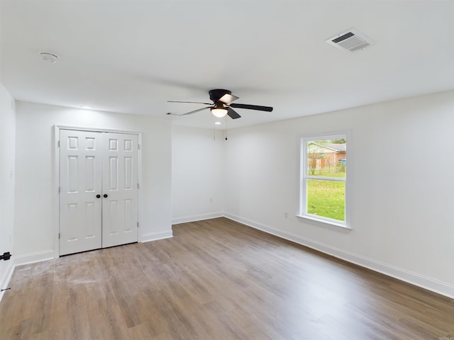 unfurnished room with baseboards, visible vents, ceiling fan, and wood finished floors