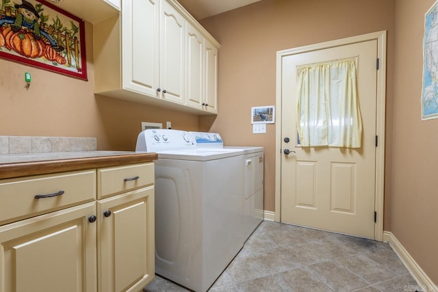 washroom featuring light tile patterned floors, washer and clothes dryer, cabinet space, and baseboards