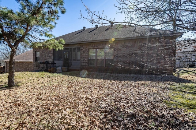 back of property featuring brick siding and a shingled roof