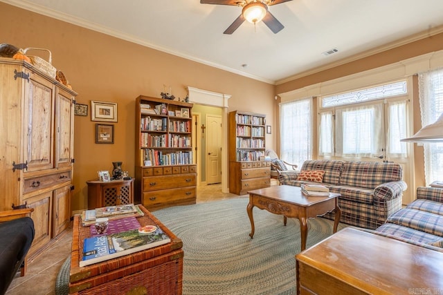 living room featuring ornamental molding, a ceiling fan, visible vents, and light tile patterned floors