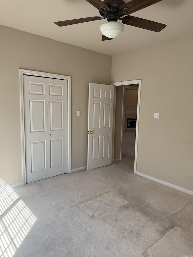 unfurnished bedroom featuring light carpet, ceiling fan, a closet, and baseboards