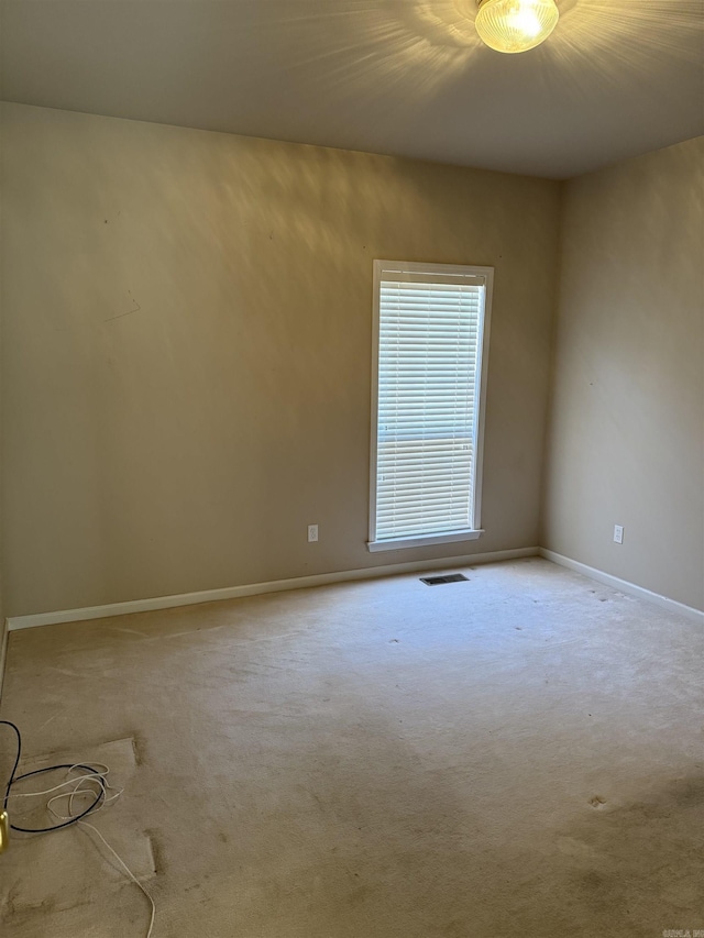 spare room featuring carpet, visible vents, and baseboards