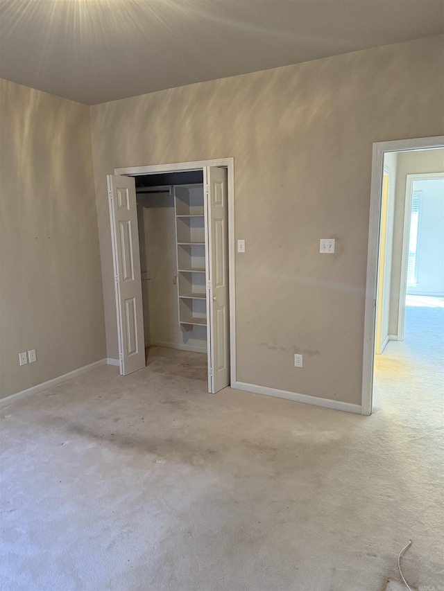 unfurnished bedroom featuring light carpet, baseboards, and a closet