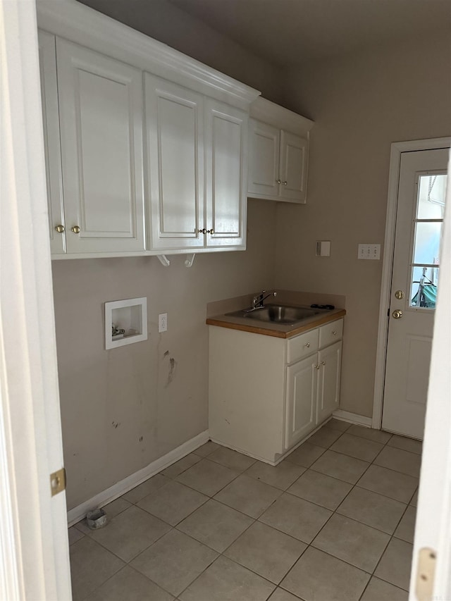 clothes washing area featuring cabinet space, baseboards, washer hookup, a sink, and light tile patterned flooring