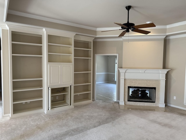 unfurnished living room with light carpet, baseboards, built in features, ornamental molding, and a glass covered fireplace