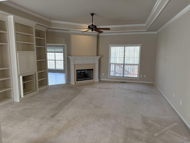 unfurnished living room featuring light carpet, a glass covered fireplace, a wealth of natural light, and baseboards