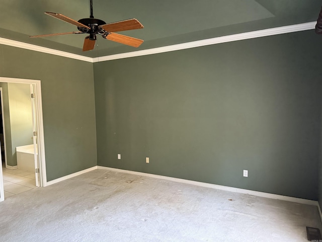 carpeted spare room featuring ceiling fan, baseboards, and crown molding