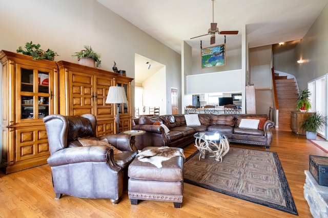 living area featuring high vaulted ceiling, ceiling fan, and light wood finished floors