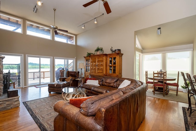 living area with a towering ceiling, light wood finished floors, ceiling fan, and rail lighting