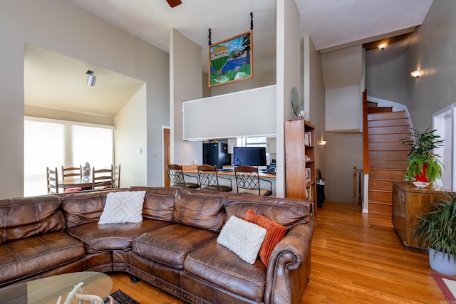 living area with stairs, a high ceiling, and wood finished floors