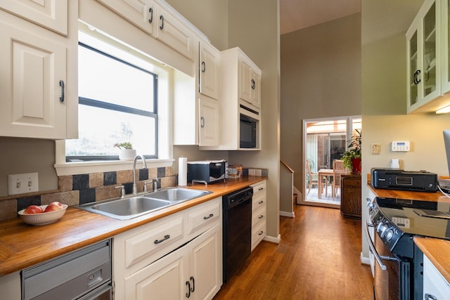 kitchen with dishwasher, butcher block countertops, stainless steel microwave, a sink, and range with electric stovetop