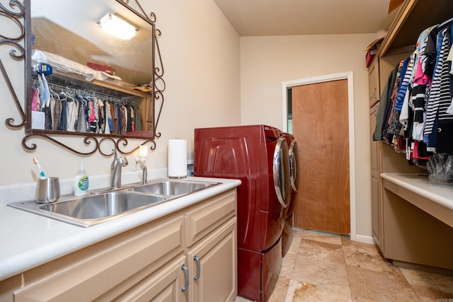 laundry room with stone finish flooring, independent washer and dryer, a sink, and cabinet space