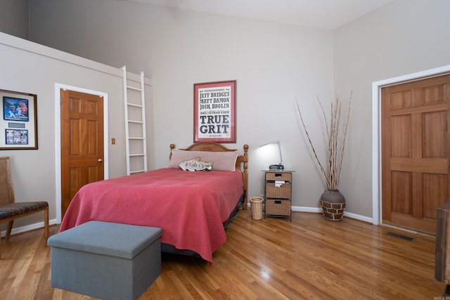 bedroom featuring visible vents, baseboards, and wood finished floors